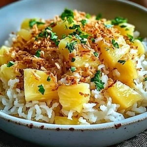 Bowl of creamy coconut pineapple rice garnished with coconut flakes and pineapple.