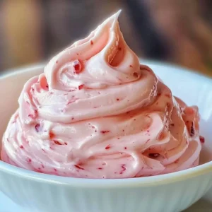 Strawberry marshmallow frosting on a cake, showcasing its fluffy texture and pink hue.